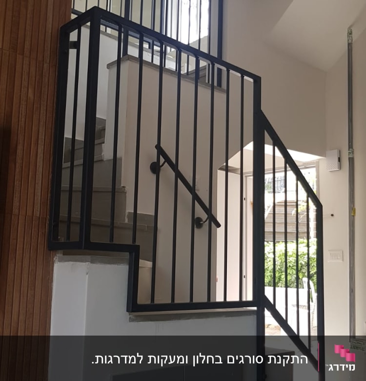 מעקה מתכת שחור על מדרגות פנימיות בבית